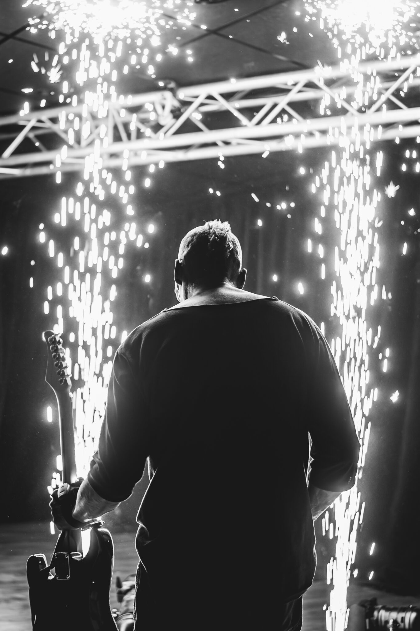 Spektakuläres Foto eines Gitarristen, der für ein Event Gitarre gespielt hat. Er ist mit dem Rücken zur Kamera gewendet