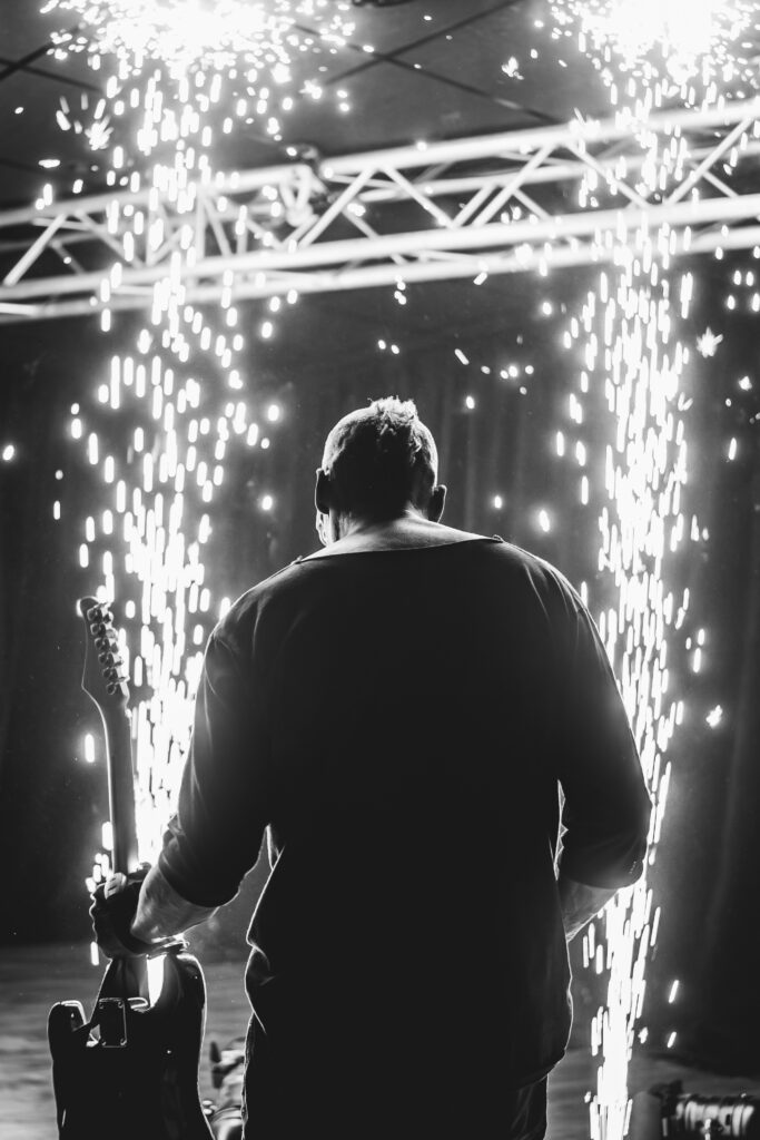 Spektakuläres Foto eines Gitarristen, der für ein Event Gitarre gespielt hat. Er ist mit dem Rücken zur Kamera gewendet